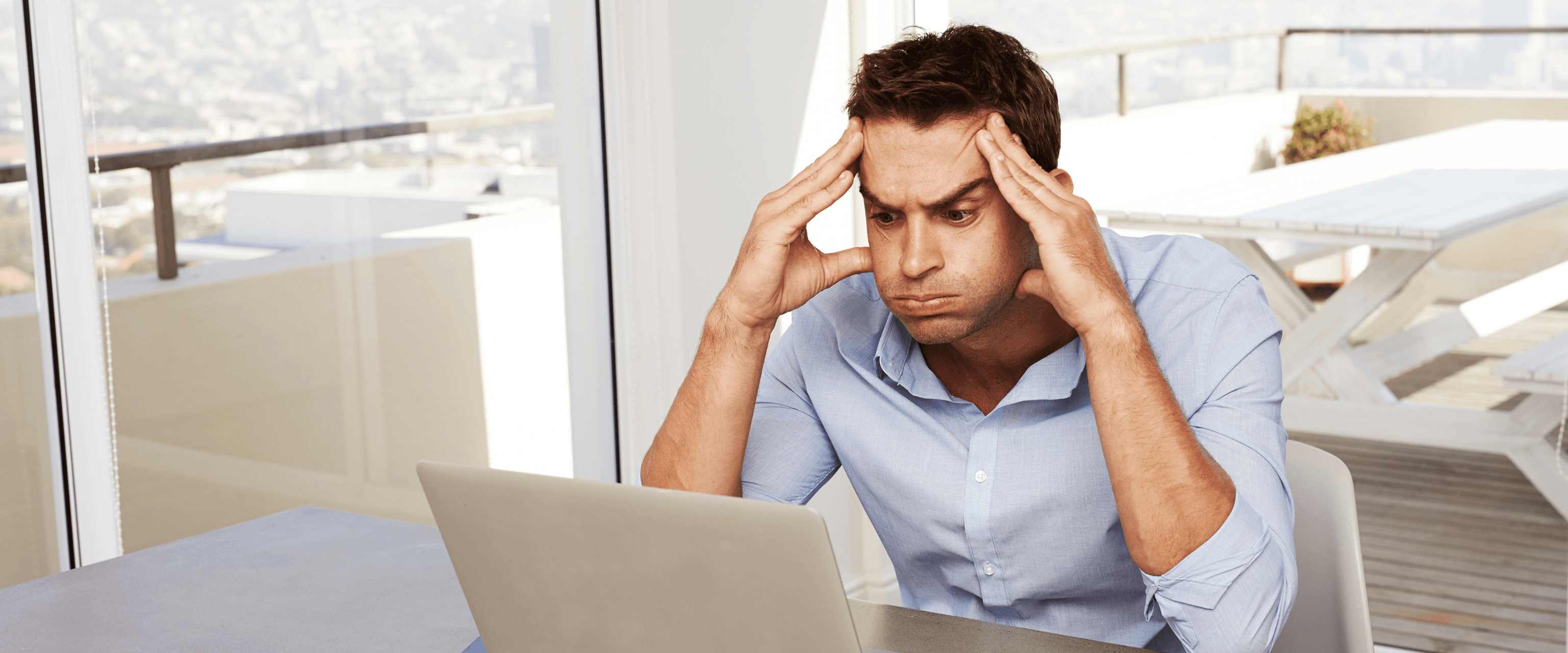 Man holding his head while looking at his laptop, trying to work out who can help him fix his credit