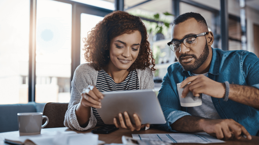 man and woman sitting at a table looking at a tablet