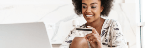 Woman on her laptop while holding a credit card.