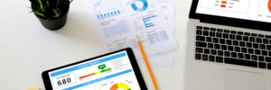 A laptop and iPad displaying a credit report with a credit score of 680.