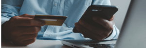 A man making his credit card payment using his phone and laptop.